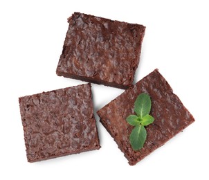 Pieces of delicious chocolate brownie with fresh mint on white background, top view