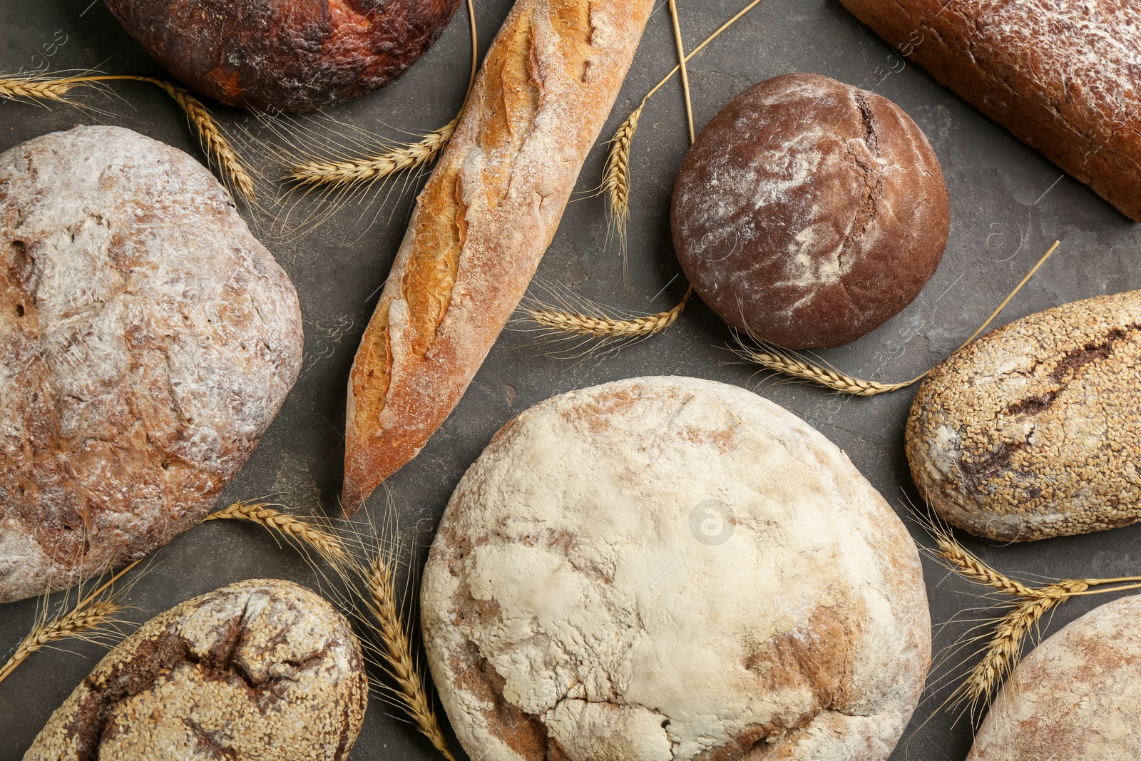 Photo of Different kinds of fresh bread on grey table, flat lay