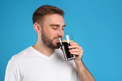 Handsome man with cold kvass on blue background. Traditional Russian summer drink