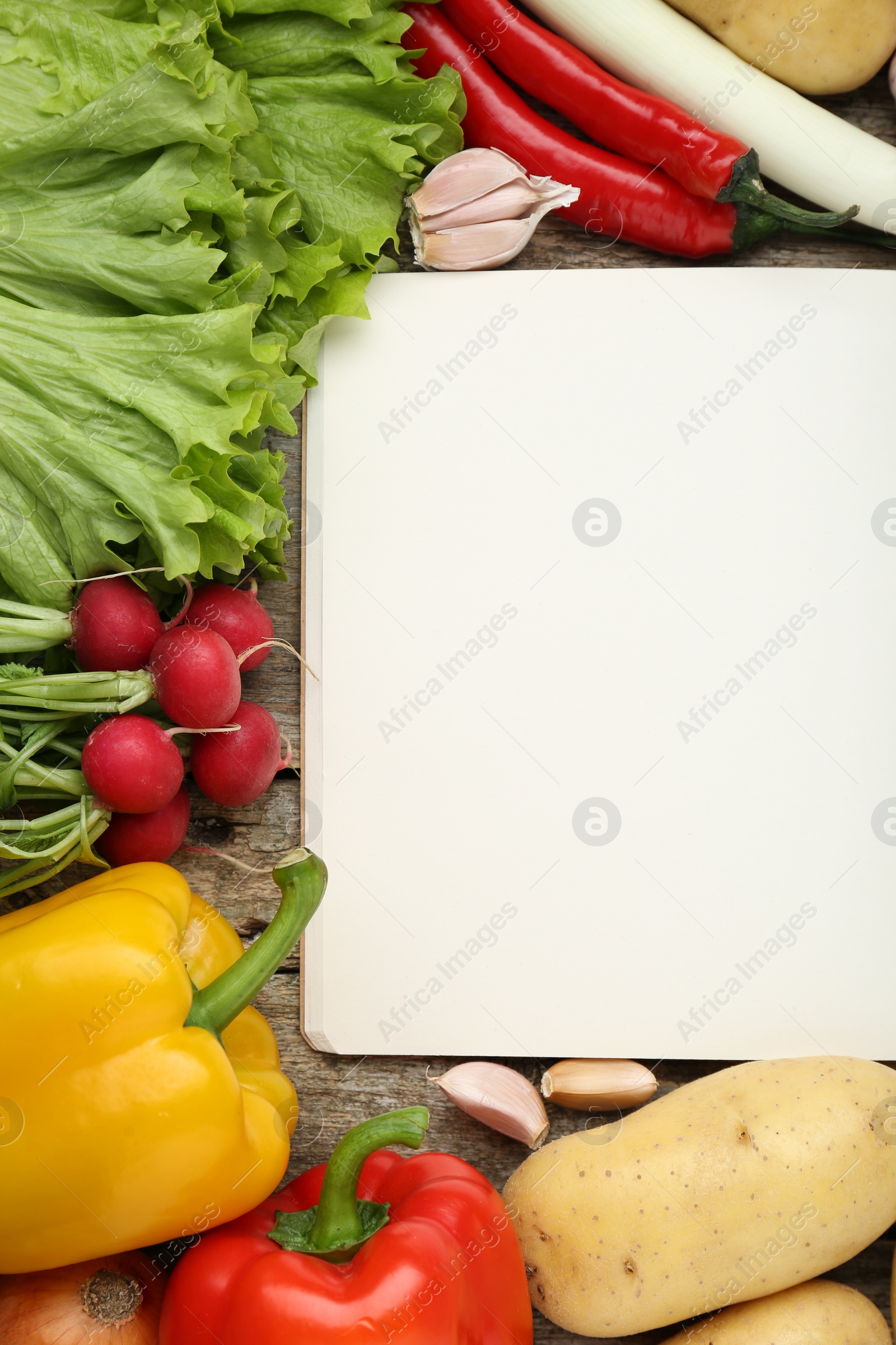 Photo of Blank recipe book and different ingredients on wooden table, flat lay. Space for text