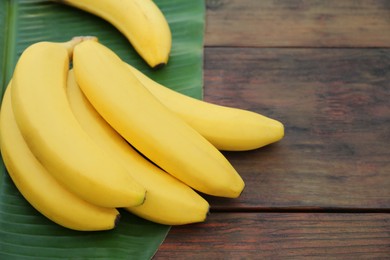 Delicious bananas and green leaf on wooden table. Space for text