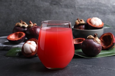 Photo of Delicious mangosteen juice and fresh fruits on dark table