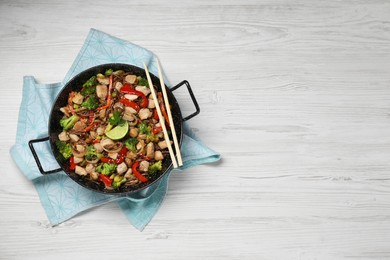 Photo of Stir-fry. Tasty noodles with meat in wok and chopsticks on white wooden table, top view. Space for text