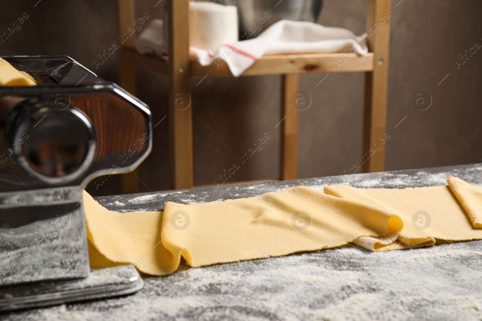 Photo of Pasta maker machine and dough on grey table