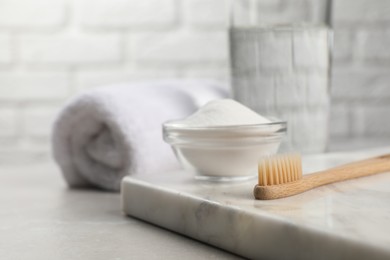 Photo of Bamboo toothbrush and glass bowl of baking soda on light table, space for text