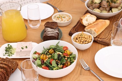 Photo of Healthy vegetarian food, glasses, cutlery and plates on wooden table