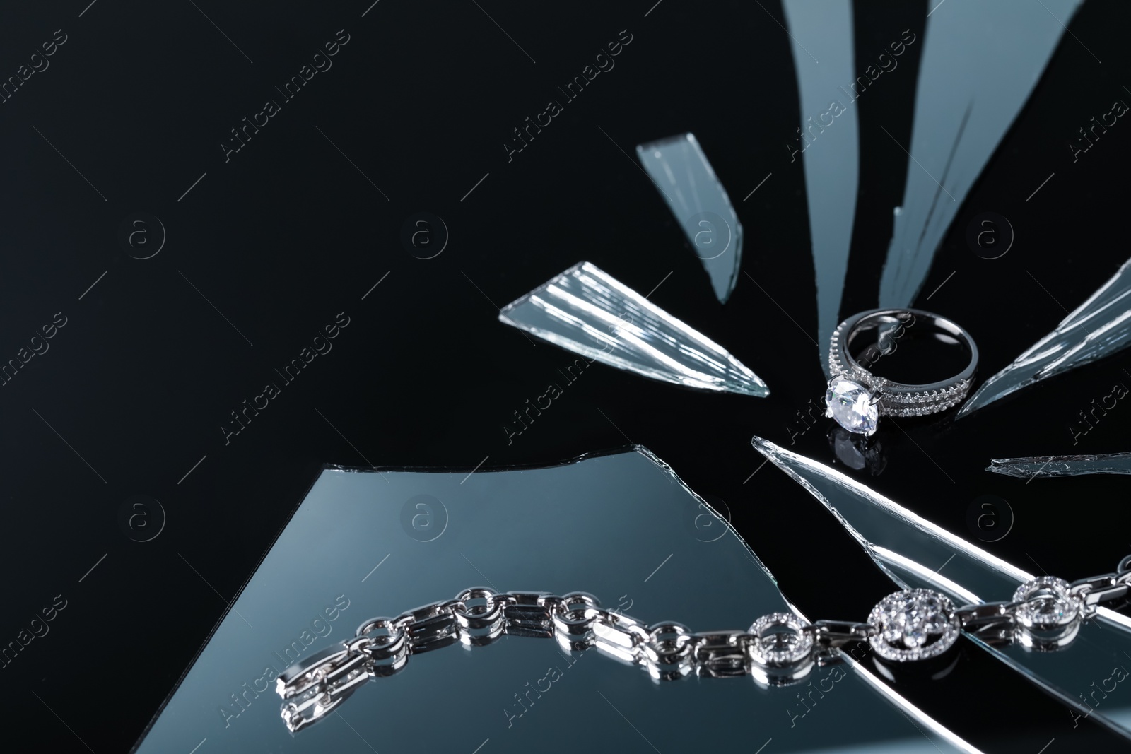 Photo of Luxury jewelry. Stylish presentation of elegant ring and bracelet on black mirror surface with broken glass, space for text