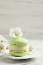 Green macaron and flowers on white marble table