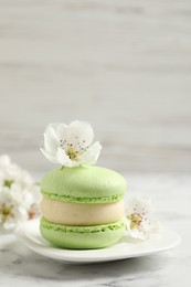 Photo of Green macaron and flowers on white marble table