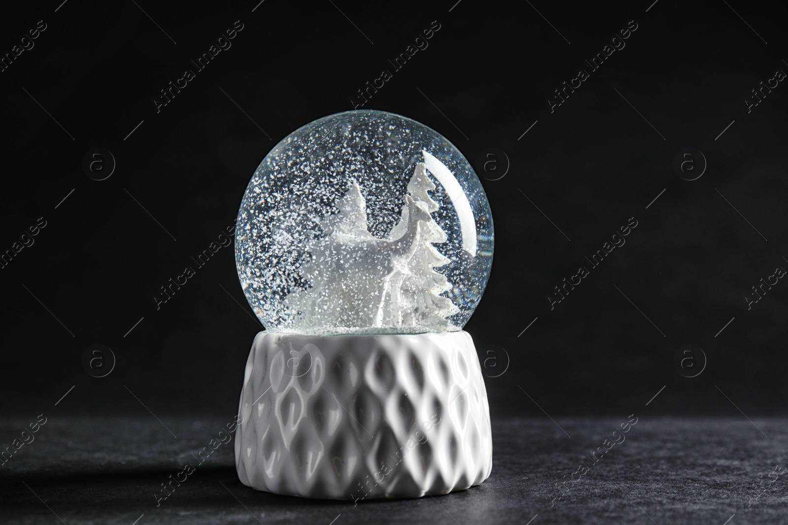 Photo of Snow globe with deer and trees on dark background