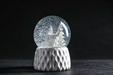 Photo of Snow globe with deer and trees on dark background