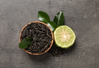 Photo of Dry bergamot tea leaves and fresh fruit on grey table, flat lay