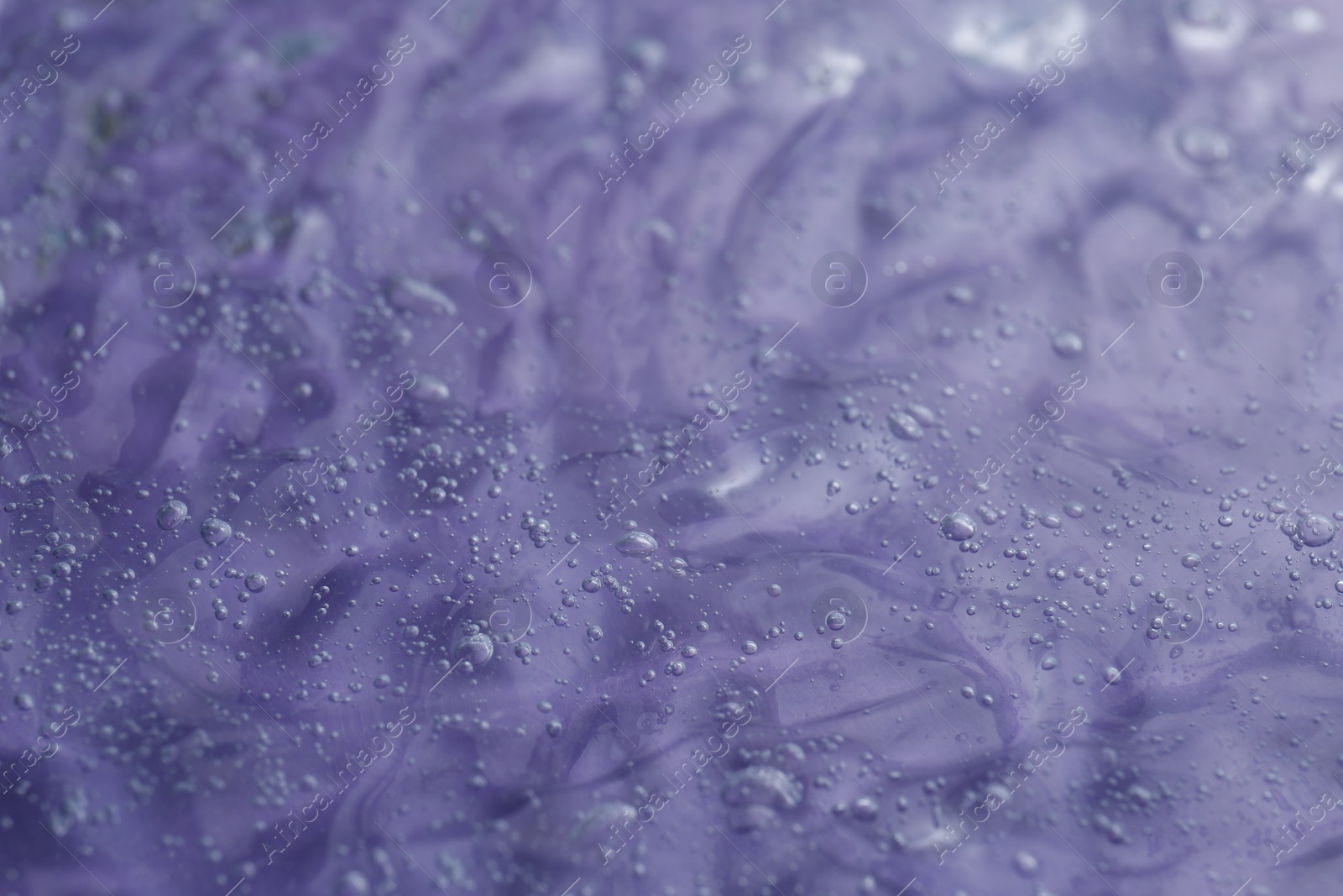 Photo of Texture of transparent shower gel on violet background, closeup