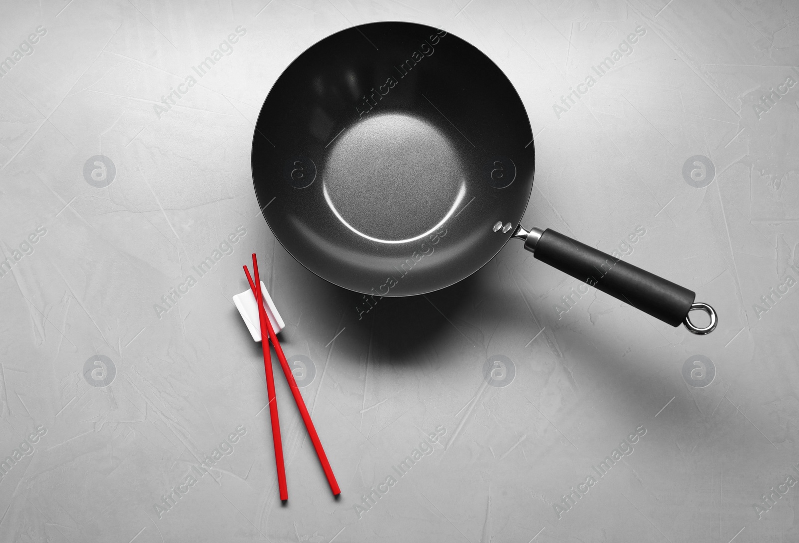 Photo of Empty iron wok and chopsticks on grey table, flat lay