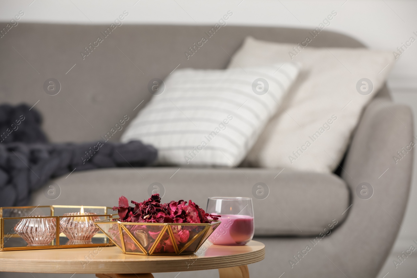 Photo of Aromatic potpourri of dried flowers in decorative bowl and burning candles on table indoors, space for text