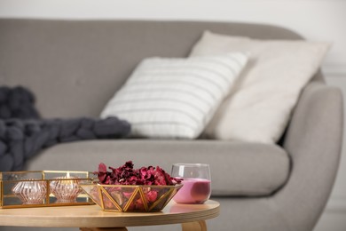 Photo of Aromatic potpourri of dried flowers in decorative bowl and burning candles on table indoors, space for text