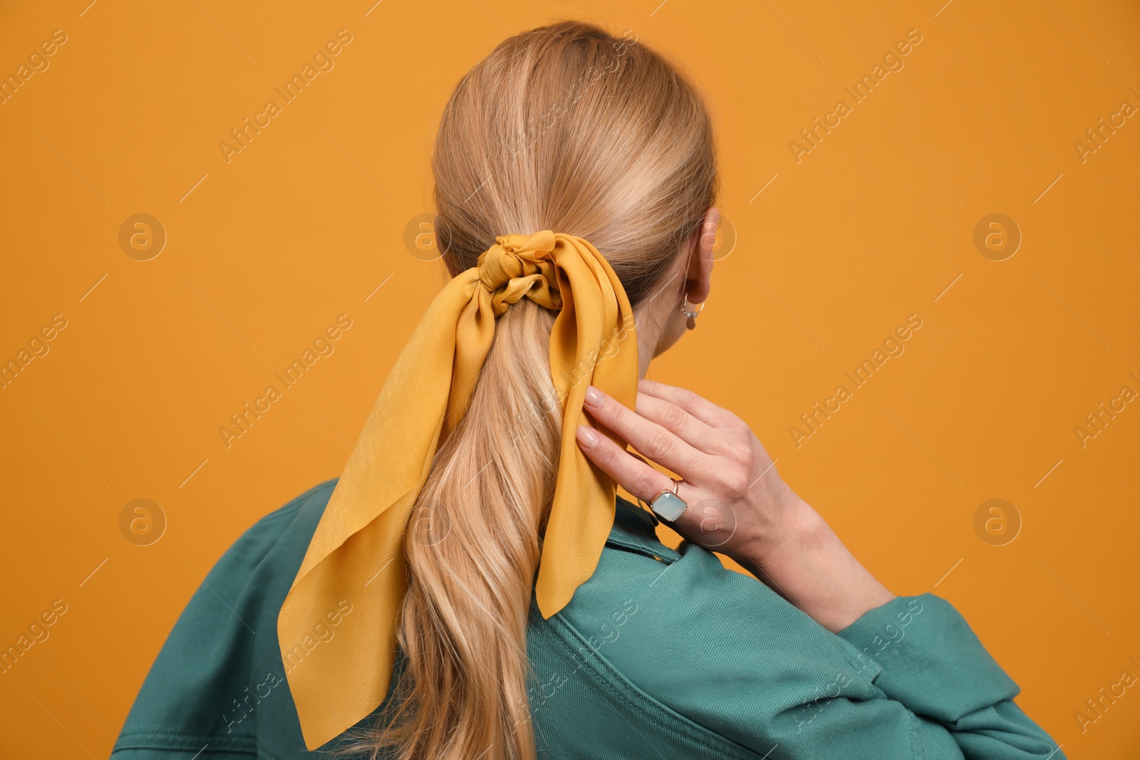 Photo of Young woman with stylish bandana on yellow background, back view