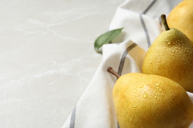 Photo of Ripe pears and striped fabric on grey background, closeup. Space for text