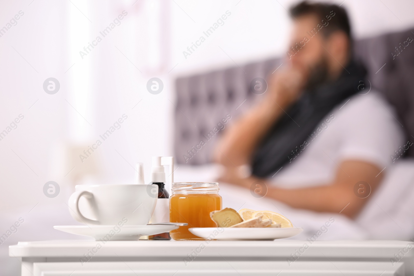 Photo of Hot tea with cough remedies and ill man on background