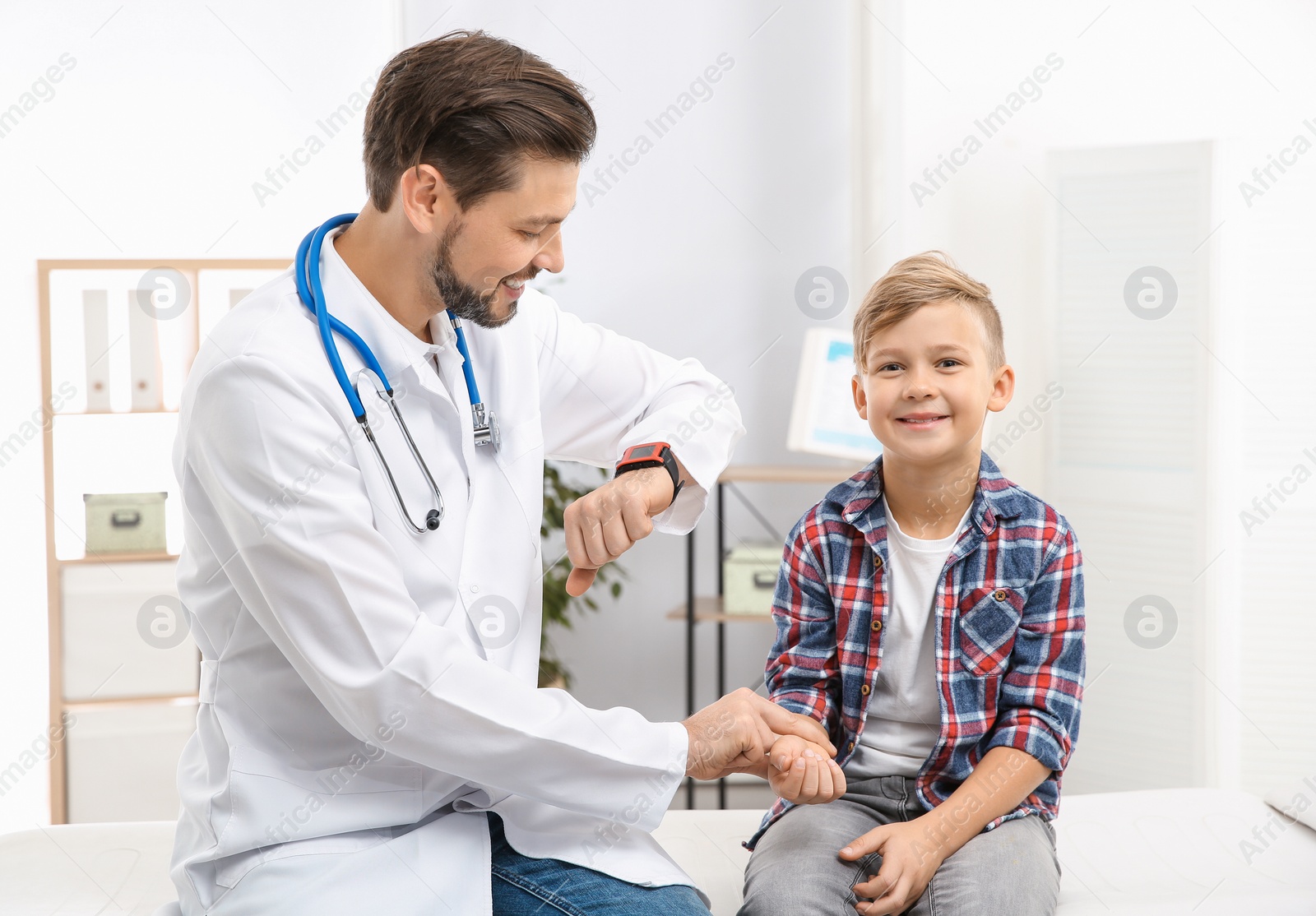 Photo of Doctor checking little boy's pulse with fingers in hospital