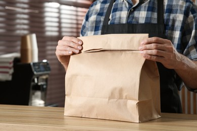 Photo of Worker with paper bag at counter in cafe, closeup