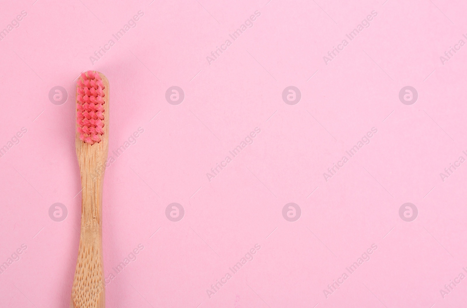 Photo of Toothbrush made of bamboo on pink background, top view. Space for text
