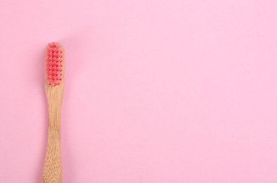Photo of Toothbrush made of bamboo on pink background, top view. Space for text