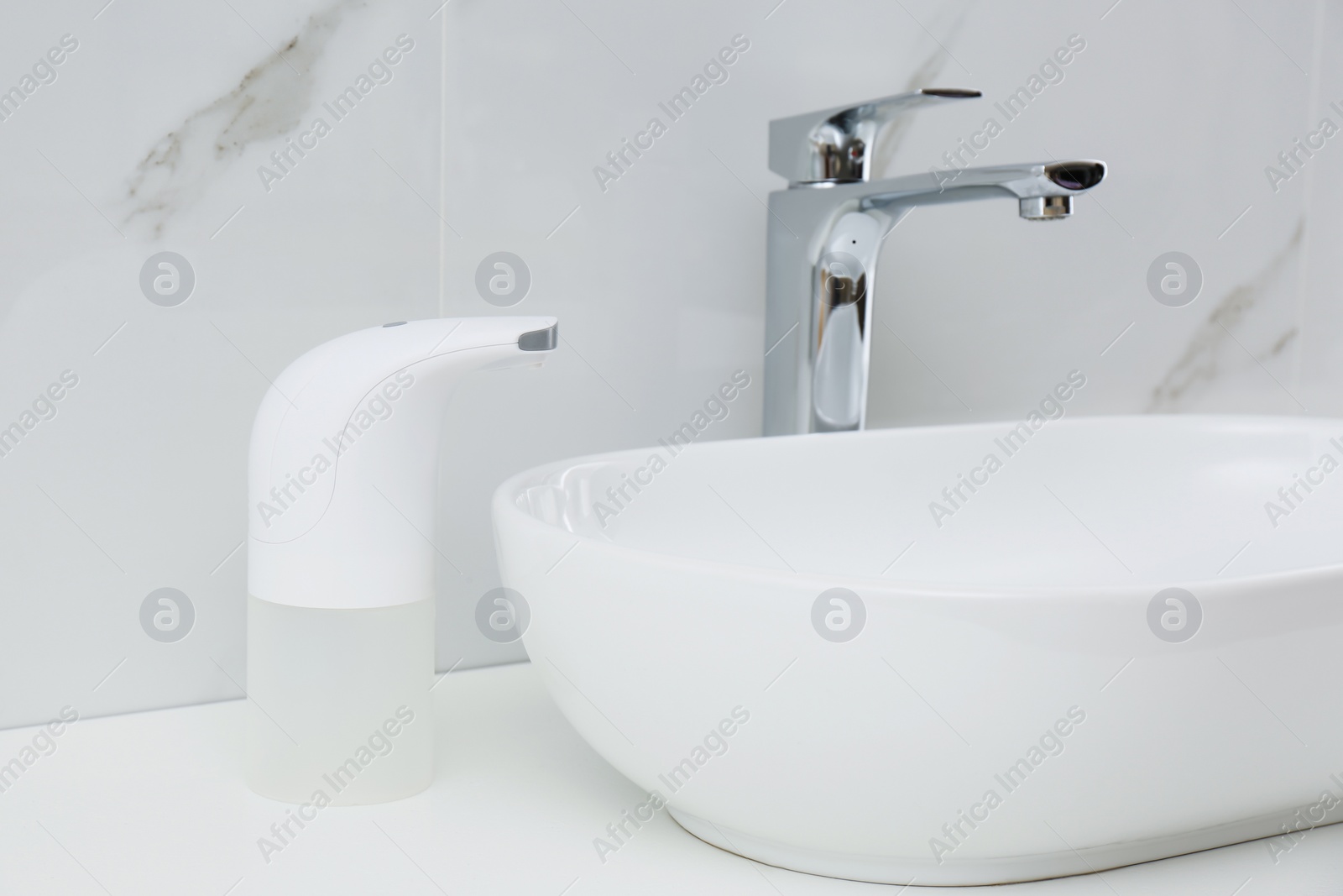 Photo of Modern automatic soap dispenser near sink in bathroom, closeup