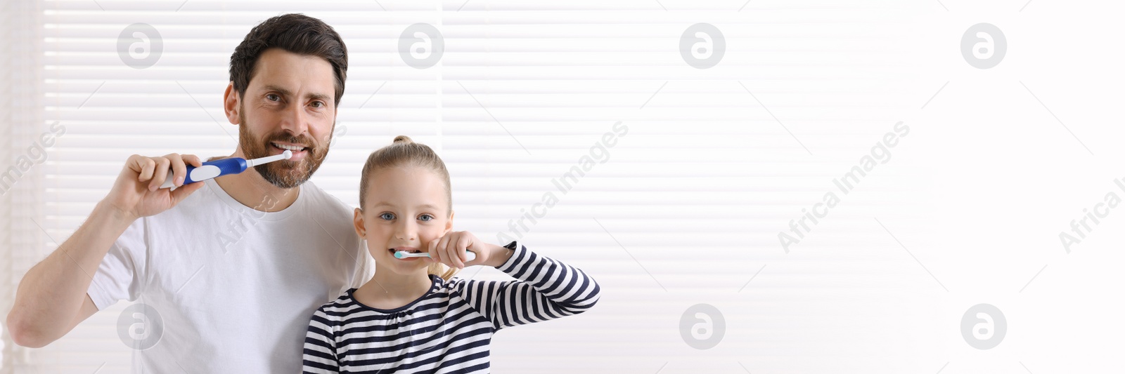 Image of Father and his daughter brushing teeth together indoors. Banner design with space for text