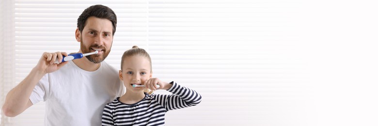 Image of Father and his daughter brushing teeth together indoors. Banner design with space for text