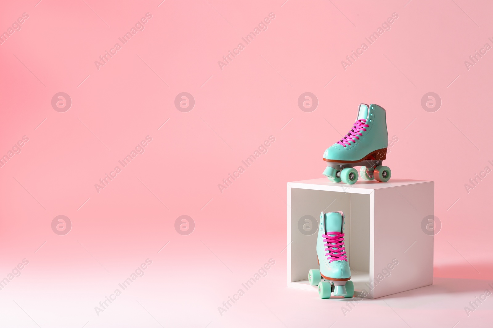 Photo of Pair of vintage roller skates and storage cube on color background. Space for text