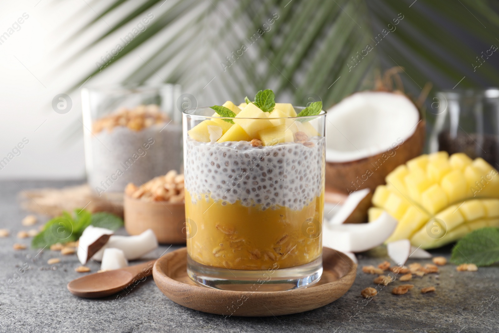 Photo of Delicious chia pudding with mango, mint and granola on grey table