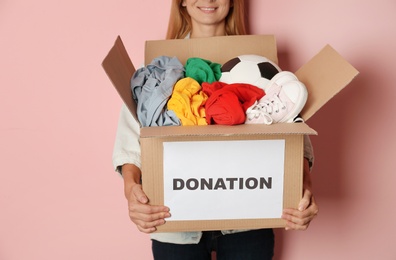 Woman holding box with donations on color background