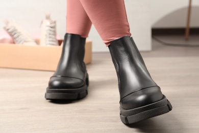 Photo of Woman wearing stylish leather boots indoors, closeup