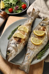 Delicious baked fish, lemon and rosemary on table