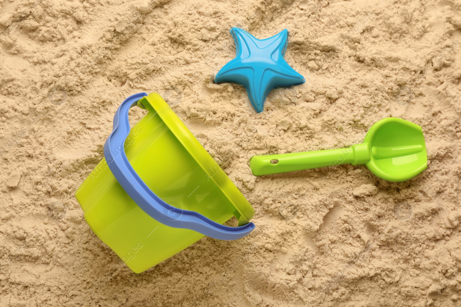 Photo of Beach toy kit on sand, flat lay. Outdoor play