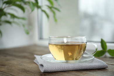 Photo of Tasty hot green tea in cup on wooden table