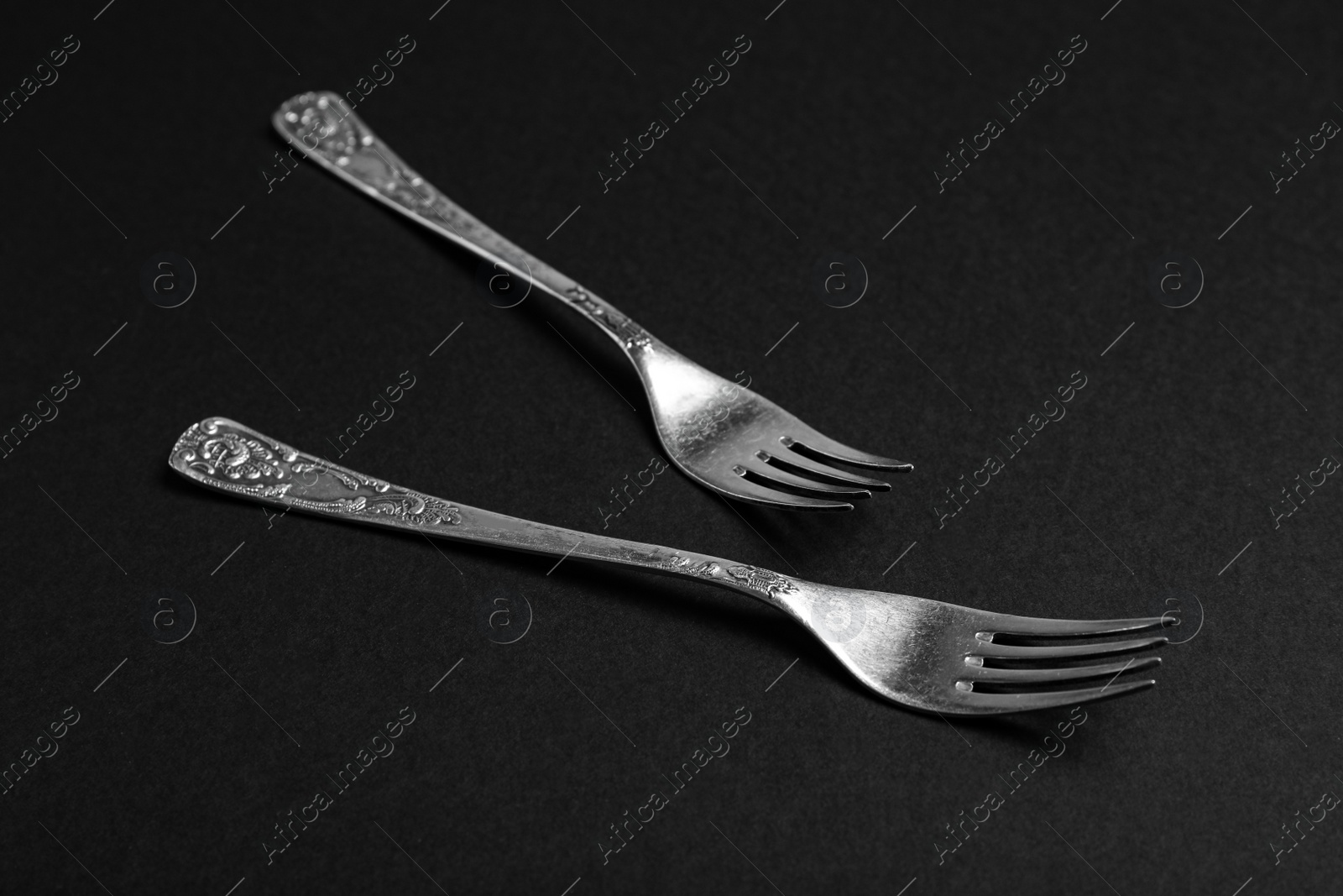 Photo of Vintage silver forks on black background, closeup