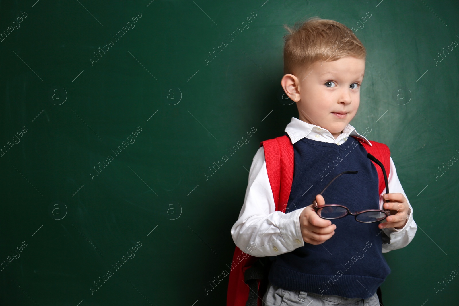 Photo of Cute little child near chalkboard, space for text. First time at school