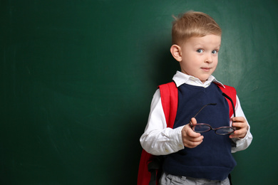 Photo of Cute little child near chalkboard, space for text. First time at school