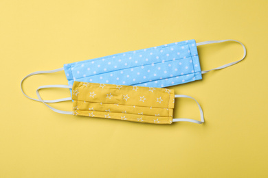 Homemade protective masks on yellow background, flat lay. Sewing idea