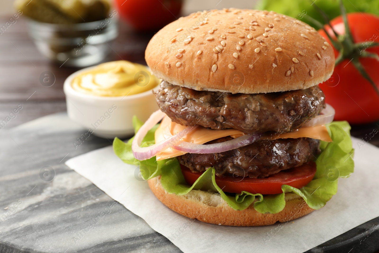 Photo of Tasty hamburger with patties, cheese and vegetables on board, closeup