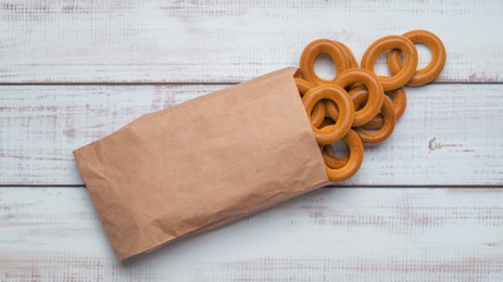Bag with tasty dry bagels (sushki) on white wooden table, top view