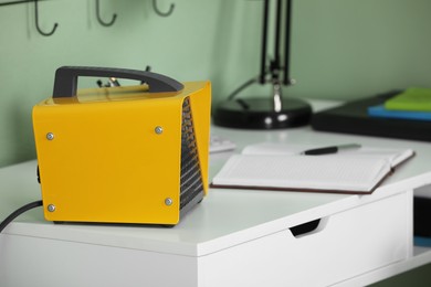 Modern electric fan heater on white table in room, closeup. Space for text