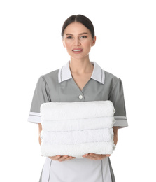 Young chambermaid holding stack of fresh towels on white background