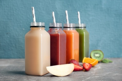 Photo of Bottles with healthy detox smoothies and ingredients on table