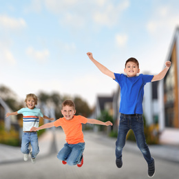 Image of Happy boys jumping on street. School holidays