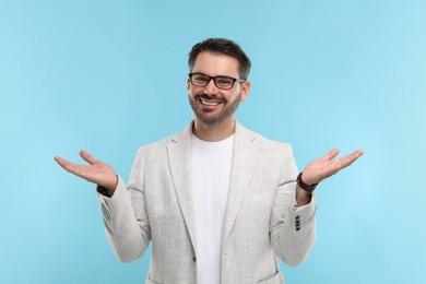 Portrait of happy man in stylish glasses on light blue background
