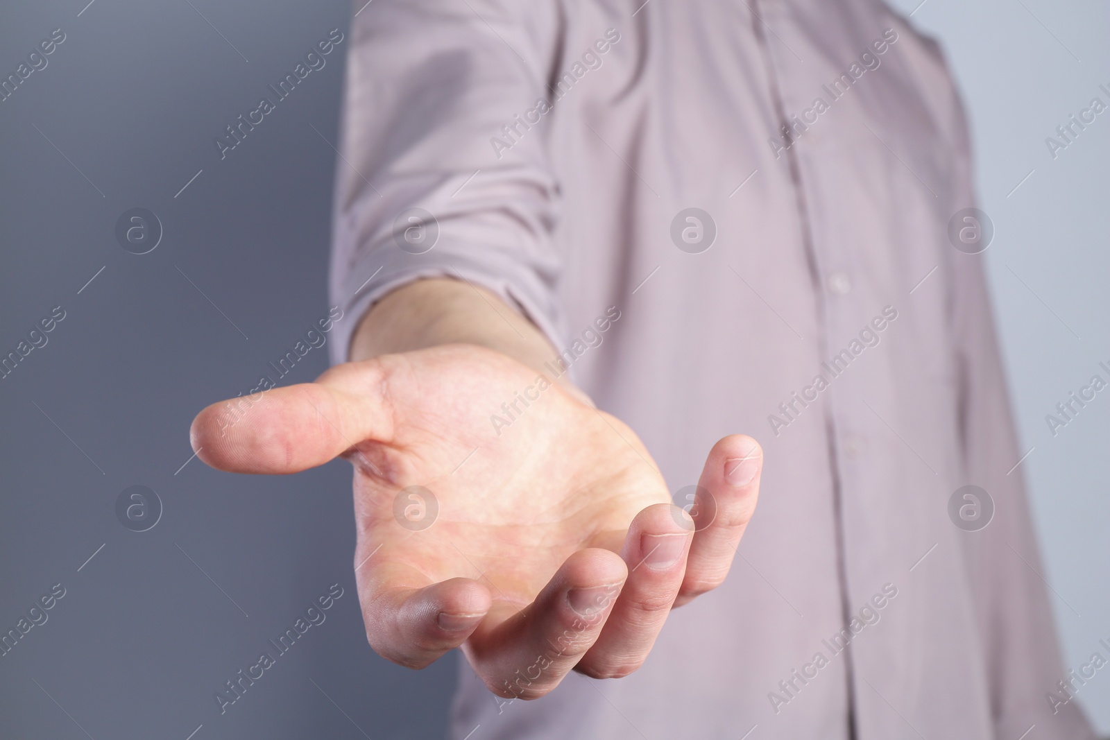 Photo of Man holding something in his hand on grey background, closeup