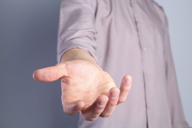Photo of Man holding something in his hand on grey background, closeup